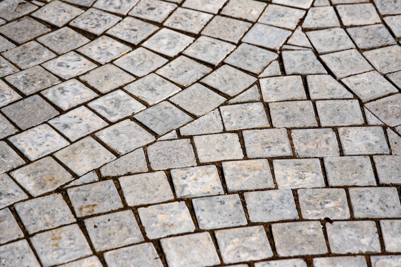 team-02 Close-up of an intricate stone pavement showcasing detailed texture and grey tones.